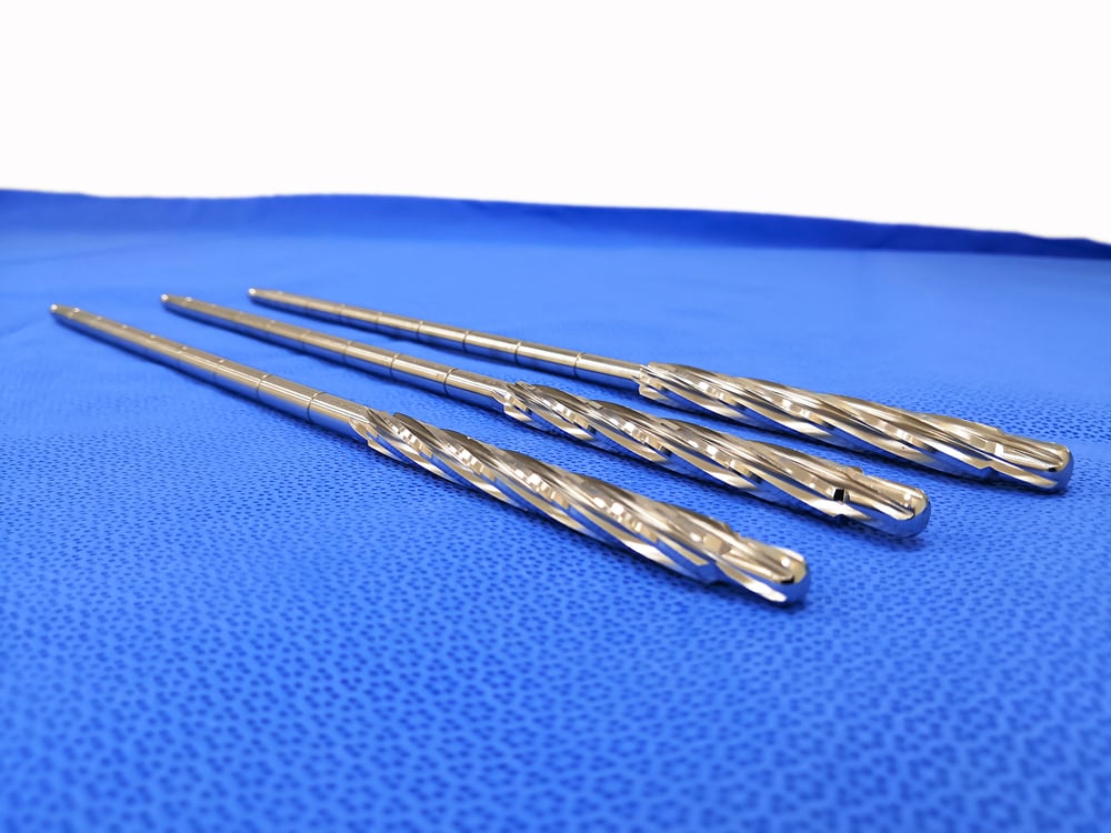 Various surgical drill bits sit on a blue surface.